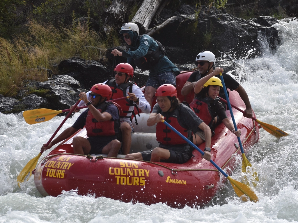 Sun Country Tours whitewater rafting on the Deschutes River, Bend Oregon — red raft through whitewater rapids